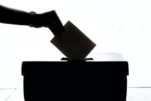 Hand wirft Wahlschein in Wahlurne