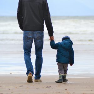 Mann mit Kind am Strand